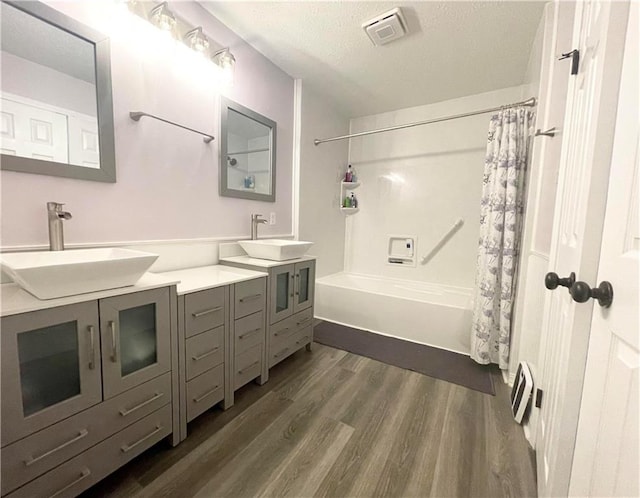 bathroom with shower / tub combo with curtain, a textured ceiling, double sink vanity, and hardwood / wood-style floors