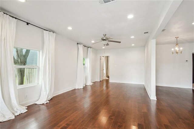 spare room featuring dark wood-type flooring and ceiling fan with notable chandelier