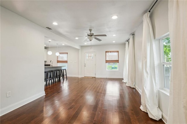 living room with sink, ceiling fan, and dark wood-type flooring