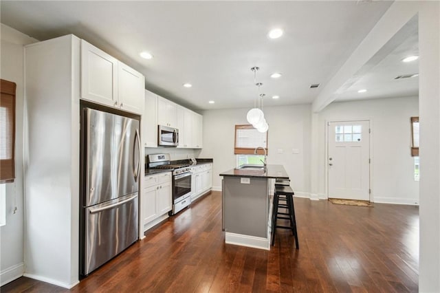 kitchen with white cabinetry, an island with sink, a breakfast bar area, dark hardwood / wood-style floors, and appliances with stainless steel finishes