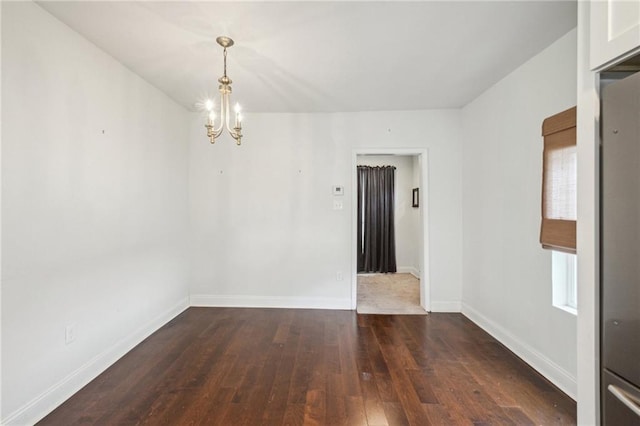 empty room with a chandelier and dark hardwood / wood-style flooring