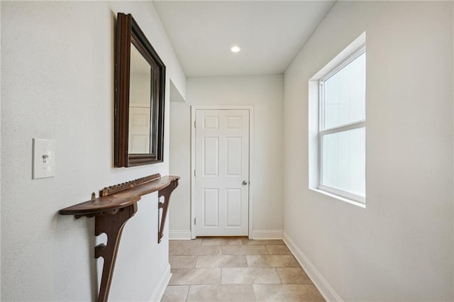 corridor with light tile patterned flooring and a wealth of natural light