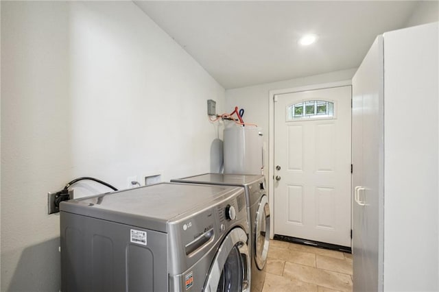 clothes washing area featuring washing machine and clothes dryer, light tile patterned flooring, and water heater