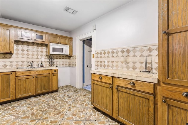 kitchen featuring tasteful backsplash, tile counters, and sink