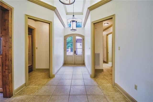 entryway with ornamental molding, light tile patterned floors, and french doors