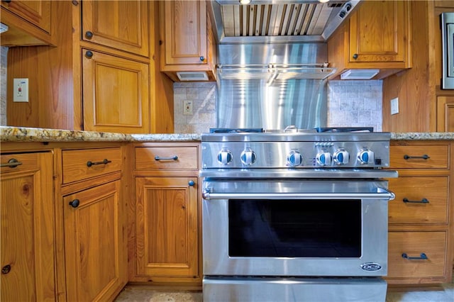 kitchen with decorative backsplash, stainless steel stove, and light stone counters