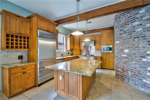 kitchen with a kitchen island, built in appliances, pendant lighting, and light stone counters