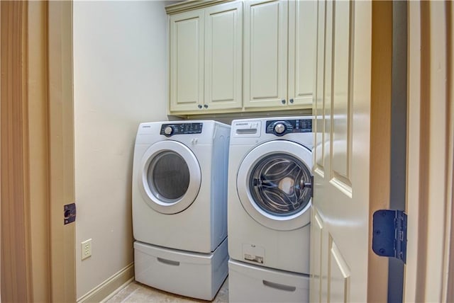 clothes washing area featuring cabinets and washer and clothes dryer