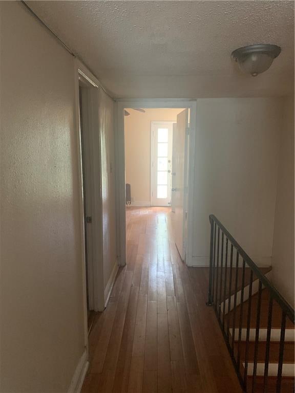 hallway with hardwood / wood-style floors and a textured ceiling