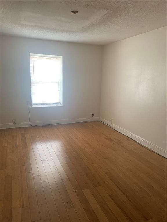 spare room featuring hardwood / wood-style floors and a textured ceiling