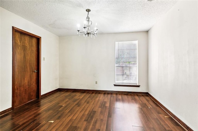 unfurnished room with a chandelier, a textured ceiling, and dark hardwood / wood-style flooring