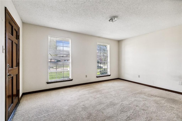 spare room with a textured ceiling and light carpet