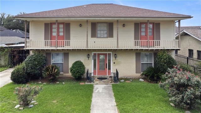 view of front of property featuring a balcony and a front lawn