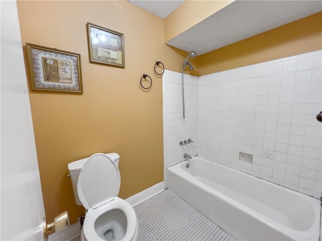 bathroom featuring tile patterned flooring, tiled shower / bath combo, and toilet