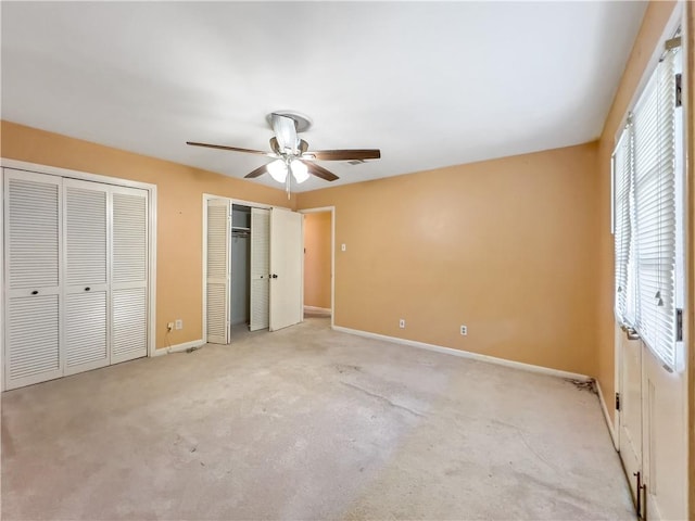 unfurnished bedroom featuring carpet flooring, two closets, and ceiling fan