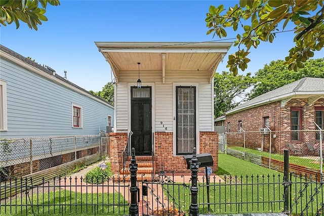 view of front of house featuring brick siding, entry steps, fence private yard, and a front lawn