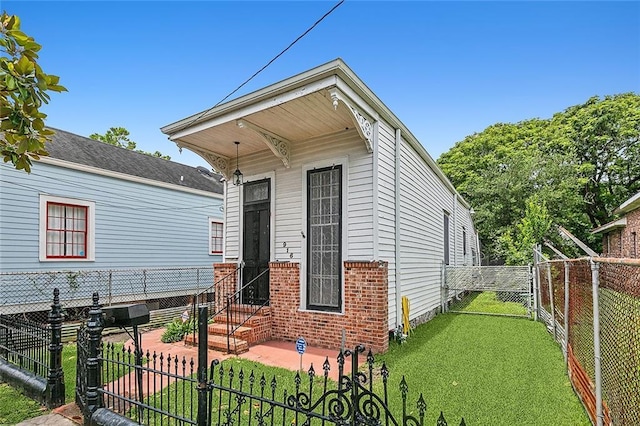 shotgun-style home with brick siding, fence private yard, a front lawn, and a gate