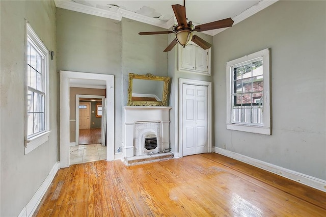 unfurnished living room featuring a fireplace, ornamental molding, ceiling fan, and light hardwood / wood-style floors