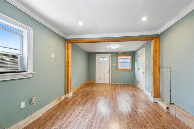 unfurnished room featuring light hardwood / wood-style floors, crown molding, and cooling unit