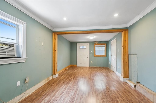 foyer entrance featuring cooling unit, baseboards, light wood-type flooring, and ornamental molding