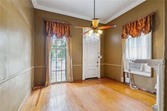 unfurnished dining area featuring ornamental molding, ceiling fan, light wood-type flooring, and cooling unit