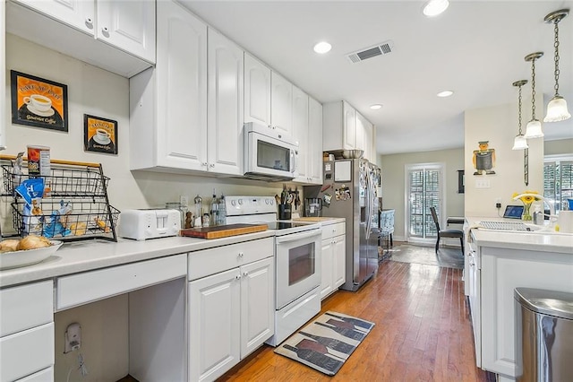 kitchen with white appliances, light wood-type flooring, white cabinets, pendant lighting, and sink