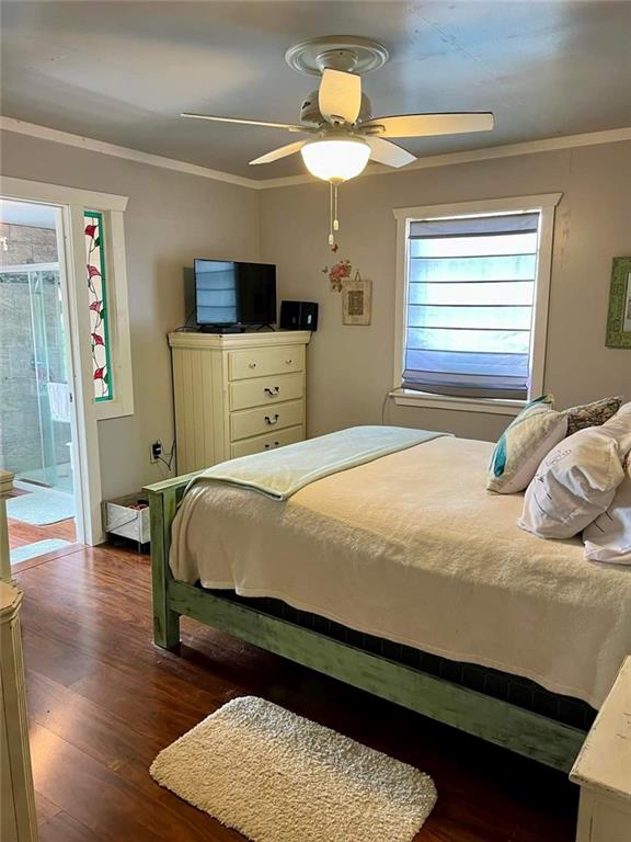 bedroom with ceiling fan, dark hardwood / wood-style flooring, ornamental molding, and multiple windows