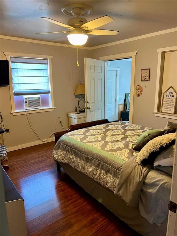 bedroom featuring cooling unit, dark wood-type flooring, ceiling fan, and crown molding