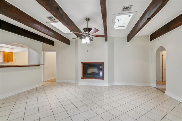 unfurnished living room with beamed ceiling, ceiling fan, and light tile patterned floors