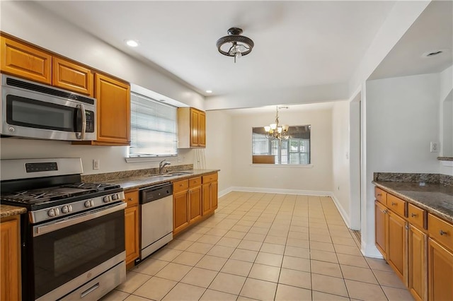 kitchen with a notable chandelier, light tile patterned floors, appliances with stainless steel finishes, decorative light fixtures, and sink