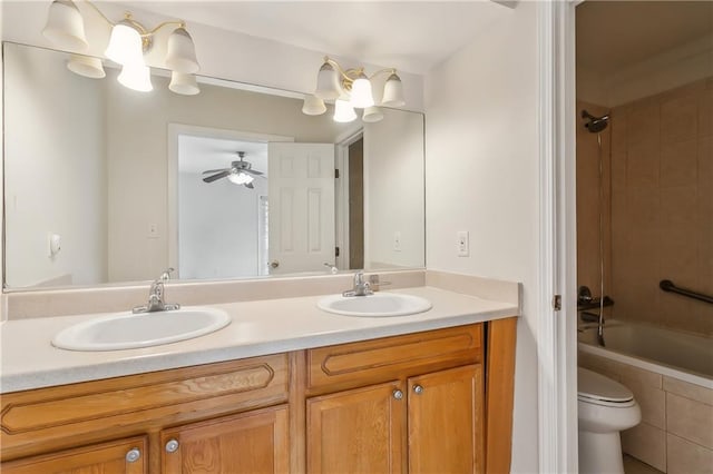 full bathroom featuring toilet, tiled shower / bath, ceiling fan, and dual bowl vanity