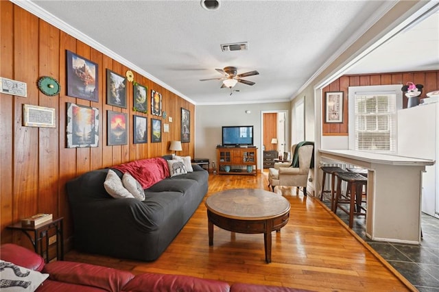 living room featuring wood walls, hardwood / wood-style flooring, and crown molding