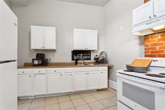 kitchen featuring white cabinets, light tile patterned flooring, and white appliances