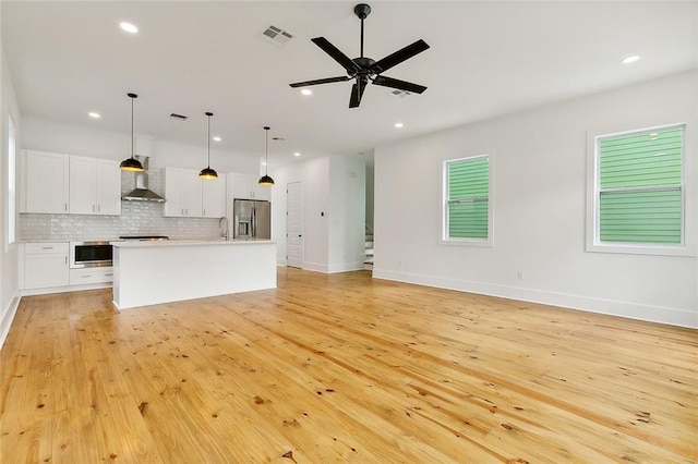 unfurnished living room featuring light hardwood / wood-style floors, sink, and ceiling fan