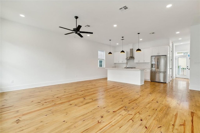 unfurnished living room featuring sink, light wood-type flooring, and ceiling fan