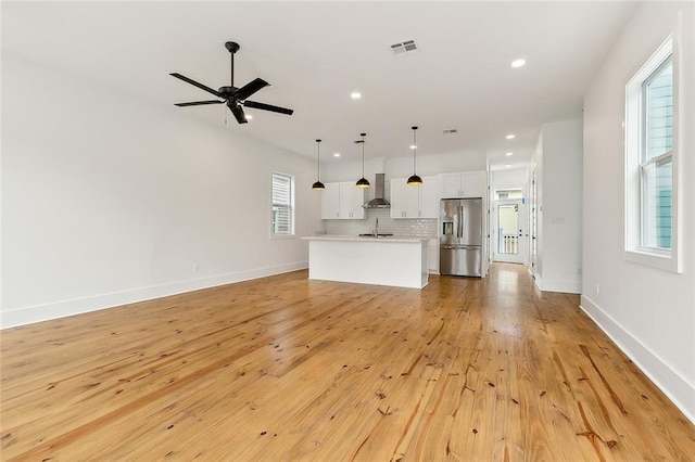 unfurnished living room featuring sink, ceiling fan, and light hardwood / wood-style floors