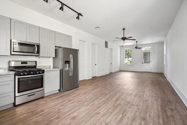 kitchen featuring stainless steel appliances, light stone counters, ceiling fan, light wood-type flooring, and gray cabinetry