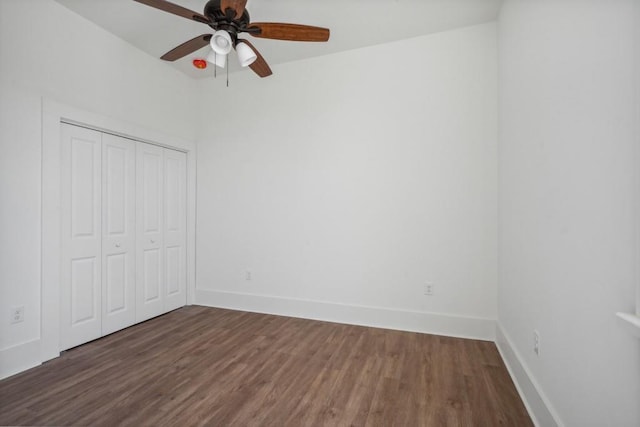 unfurnished bedroom with dark wood-type flooring, ceiling fan, and a closet