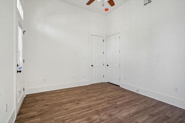 empty room with a towering ceiling, ceiling fan, and dark hardwood / wood-style floors