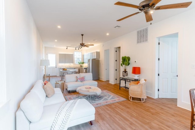 living room featuring ceiling fan and light hardwood / wood-style floors