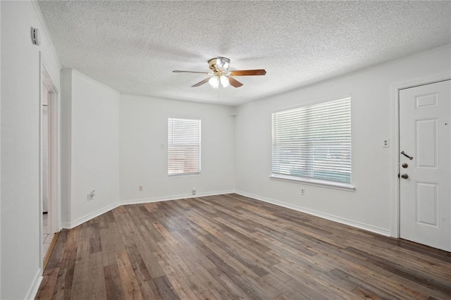 spare room featuring a textured ceiling, a healthy amount of sunlight, ceiling fan, and dark hardwood / wood-style floors