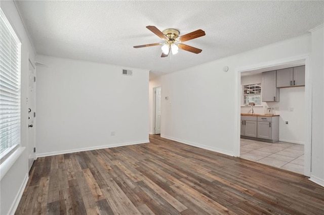 unfurnished living room with a textured ceiling, hardwood / wood-style flooring, and ceiling fan