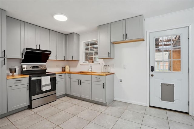 kitchen with gray cabinetry, wooden counters, light tile patterned floors, stainless steel electric range oven, and custom exhaust hood