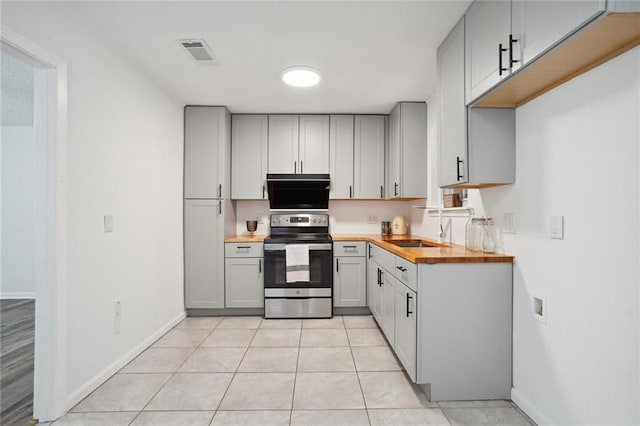 kitchen featuring butcher block countertops, sink, gray cabinets, stainless steel electric range oven, and light tile patterned flooring