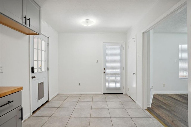 interior space featuring ornamental molding, light tile patterned flooring, and a healthy amount of sunlight