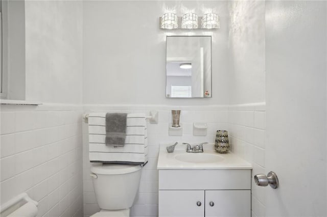 bathroom featuring vanity, toilet, and tile walls