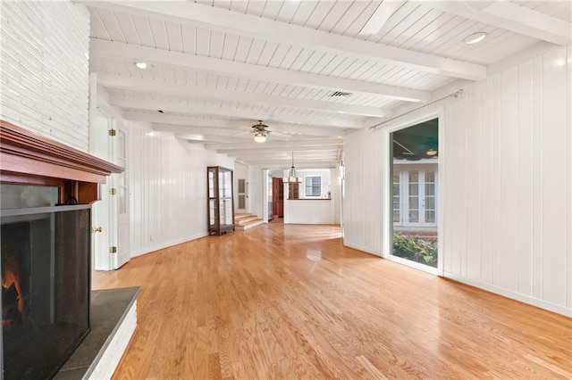 unfurnished living room with beamed ceiling, light wood-type flooring, and a large fireplace