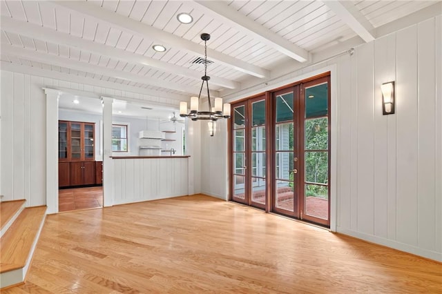 unfurnished dining area with decorative columns, beamed ceiling, light tile patterned floors, and an inviting chandelier