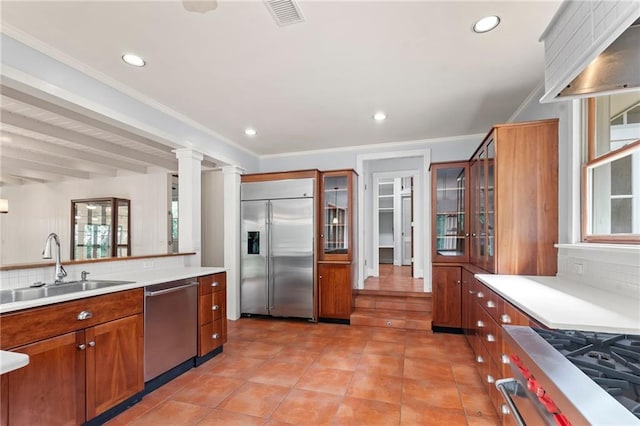 kitchen with light tile patterned flooring, backsplash, appliances with stainless steel finishes, ornate columns, and sink