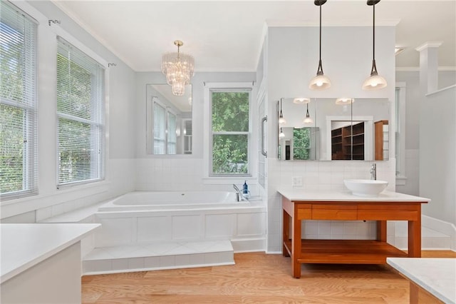 bathroom with vanity, wood-type flooring, crown molding, plenty of natural light, and a bath